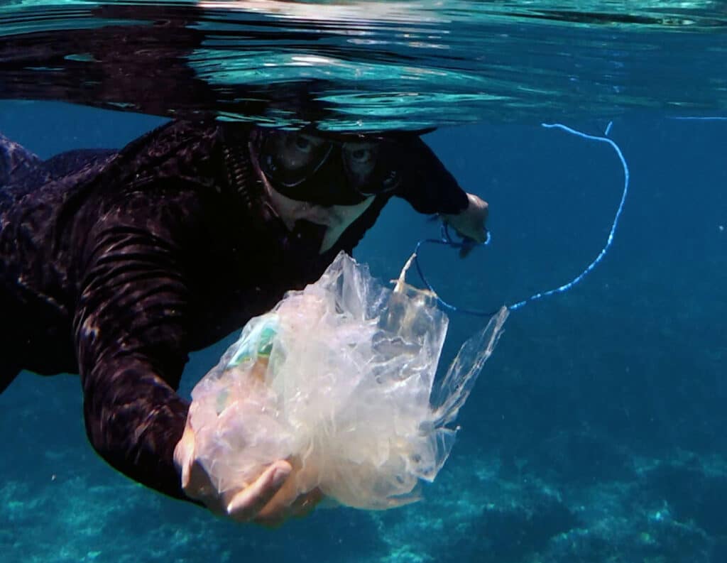 Snorkeller holding a bunch of plastic pollution collected during a dive. 