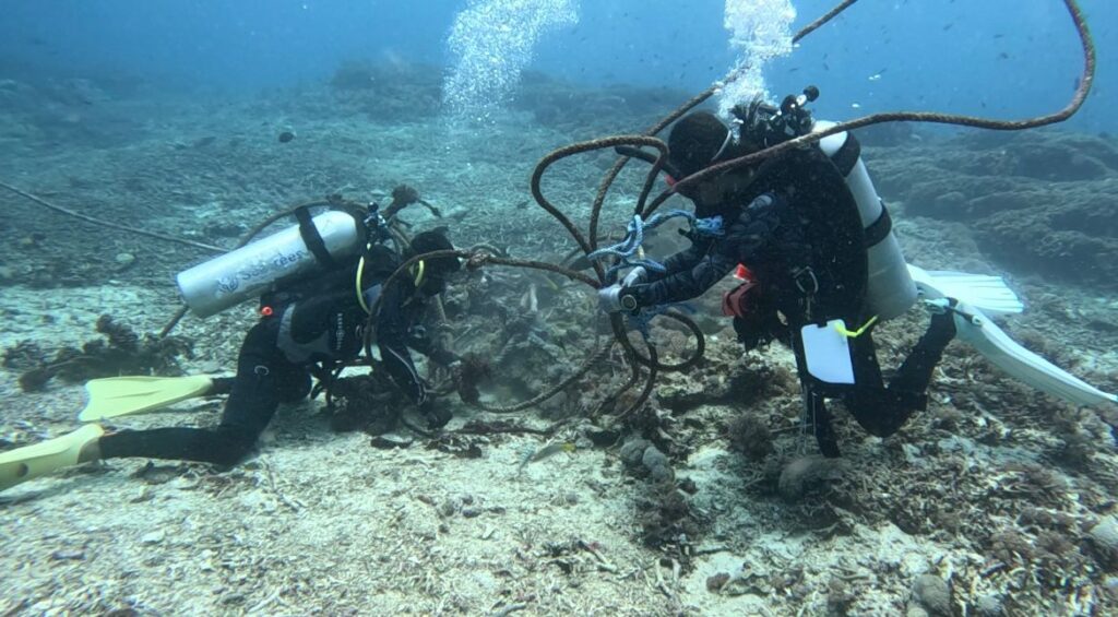 Scuba divers repositioning mooring buoy to prevent anchor damage to corals