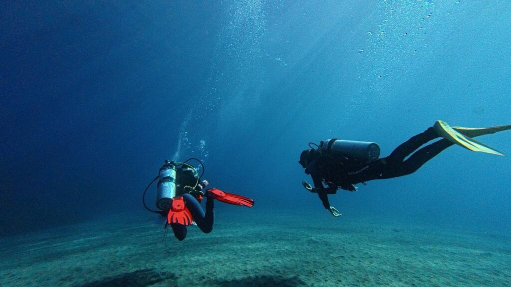 Two divers descending together with gear streamlined and tucked in, avoiding anything that could snag or drag near the reef
